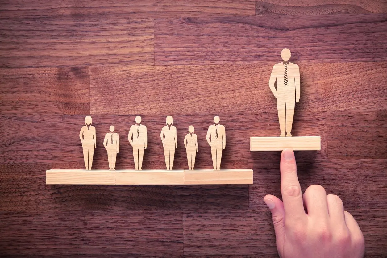 A person is standing over a row of wooden figures.