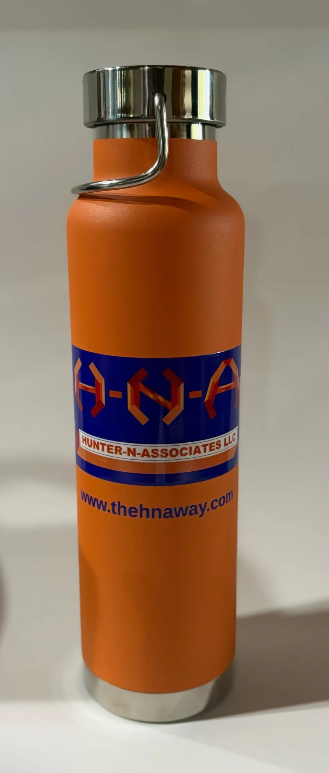 Orange water bottle with logo and website.